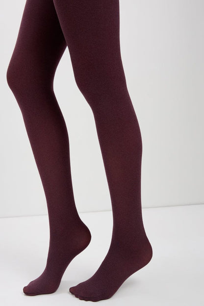A pair of opaque maroon tights worn on a person's legs against a plain white background.