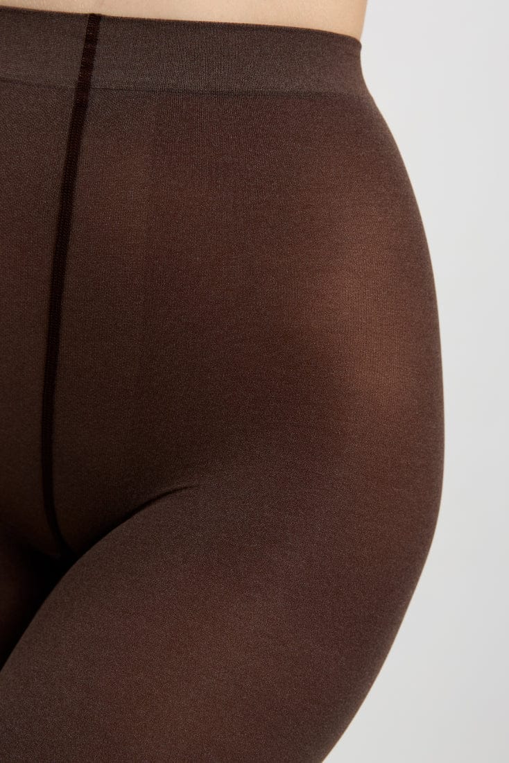 A close-up view of opaque, dark brown tights worn on a person, focusing on the seamless construction of the waistband and the smooth texture of the fabric.