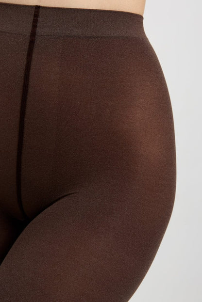 A close-up view of opaque, dark brown tights worn on a person, focusing on the seamless construction of the waistband and the smooth texture of the fabric.