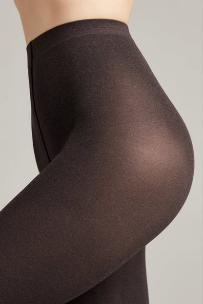 A close-up side view of dark brown, sheer tights worn on a person, featuring a high-waisted design against a plain light gray background.