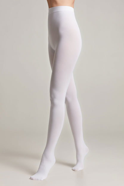 A pair of opaque white tights worn on a person's legs against a neutral grey studio background.