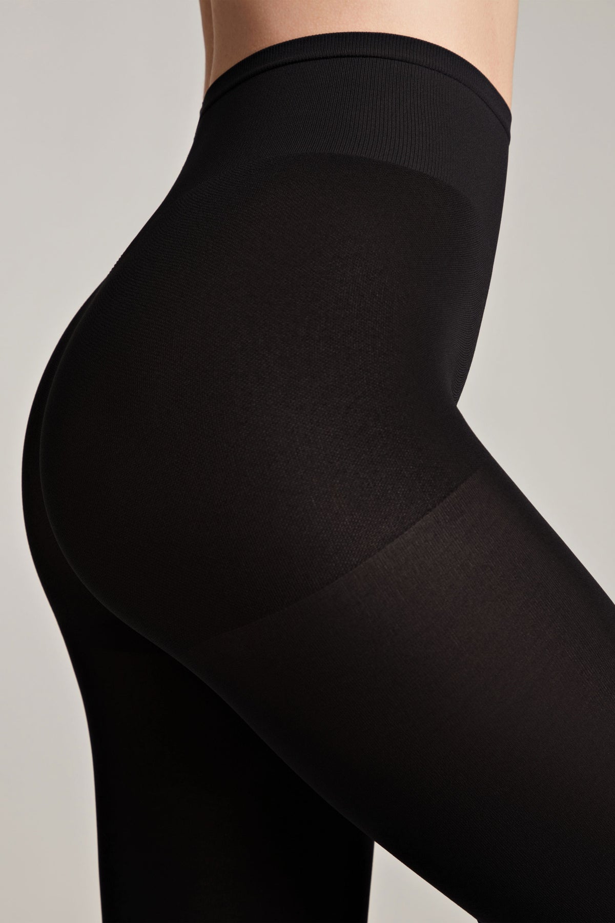Black opaque high-waisted shaping tights worn by a person, featuring a reinforced control top panel and smooth seamless texture.