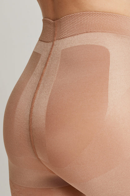 Nude-colored shaping tights feature a high-waist band, a vertical back seam, and structured control panels around the hips and rear.