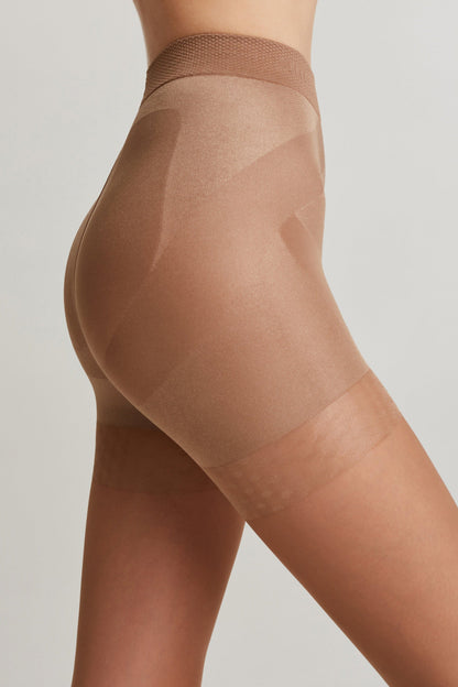 A close-up side profile view of beige, high-waisted shaping shorts with a reinforced texture panel and a semi-sheer finish on the thighs against a light grey background.