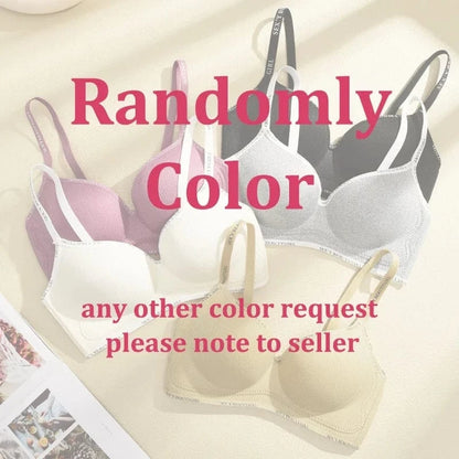 Four bras in beige, white, pink, and black are arranged on a surface, each featuring ribbed cups and straps printed with the words sexy beauty girl.