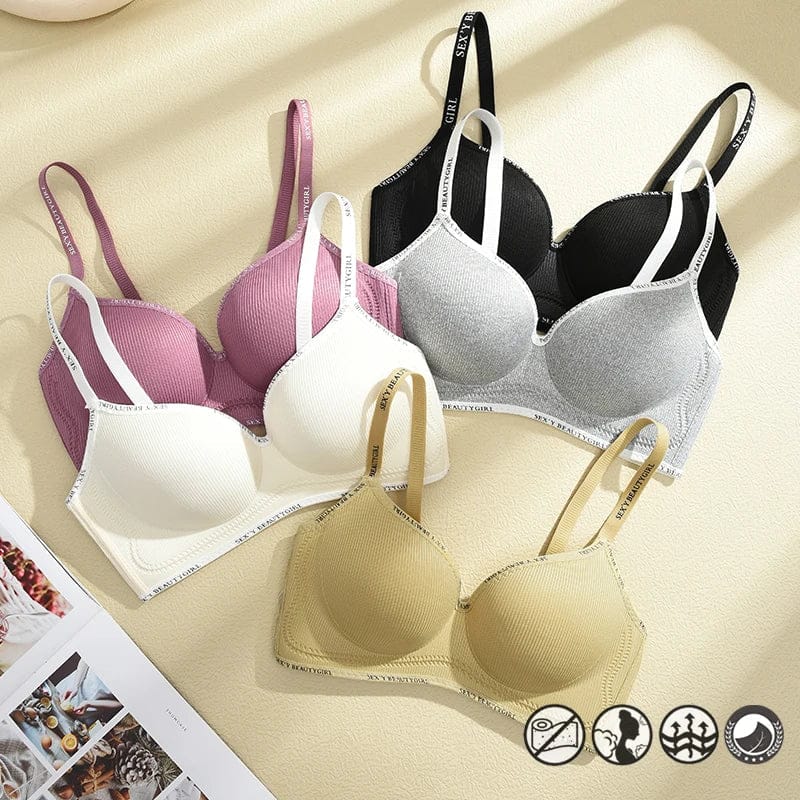 Three bras in white, black with grey, and tan colors are arranged on a beige surface, each featuring ribbed fabric, adjustable straps with text, and an underbust band.