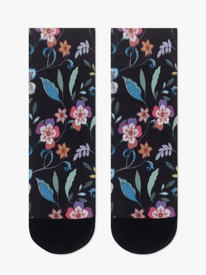 A pair of black ankle socks featuring a vibrant, multicolored floral print with various flowers, leaves, and thin stems.