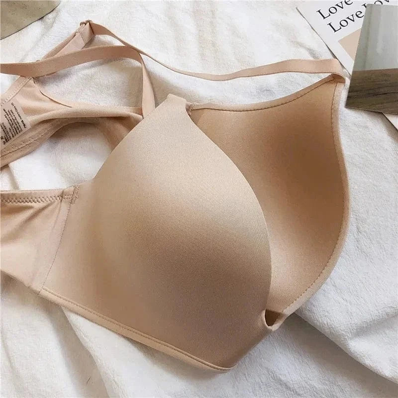 A beige molded-cup bra with adjustable straps sits on a textured white fabric surface.