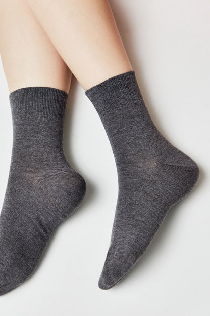 A pair of charcoal grey mid-calf socks worn on a person's feet against a plain white background.