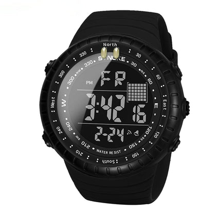 A black digital sports watch with a circular face and silicone strap displays the time, date, and day of the week on its luminous LCD screen.