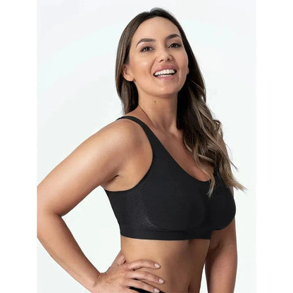 A woman with long wavy brown hair smiles while wearing a black seamless sports bra against a plain white background.