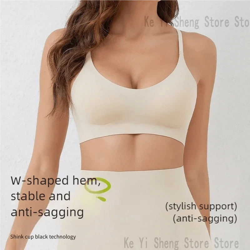 A beige seamless sports bra with a w-shaped hem is worn by a woman against a plain white background.