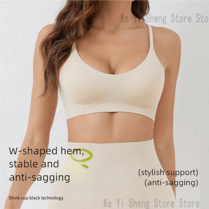 A beige seamless sports bra with a w-shaped hem is worn by a woman against a plain white background.