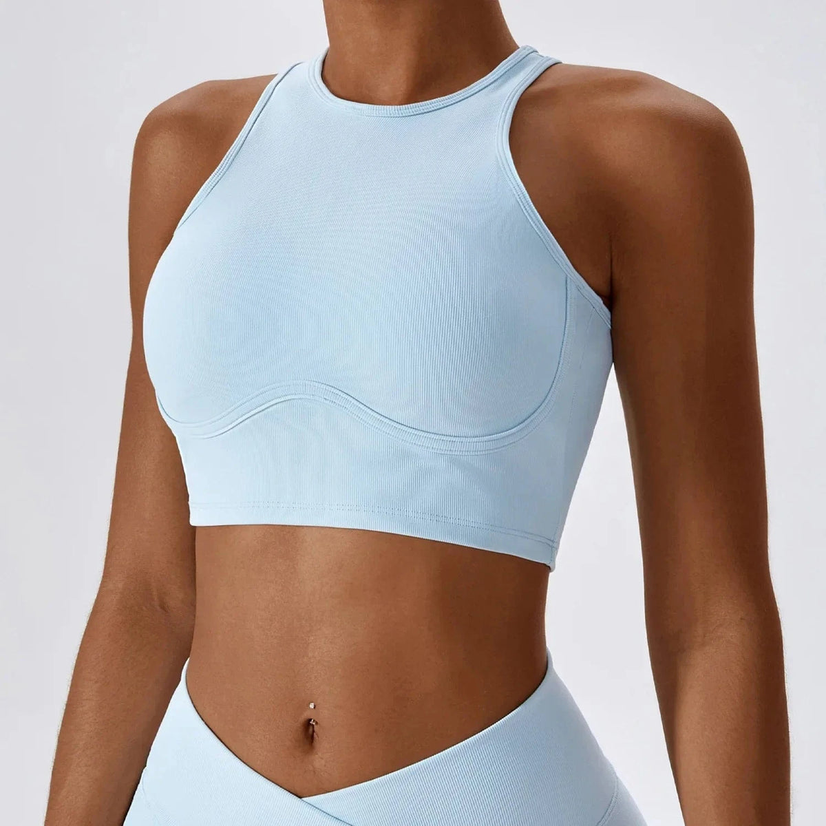 A light blue high-neck ribbed crop top with a curved under-bust seam worn by a person.