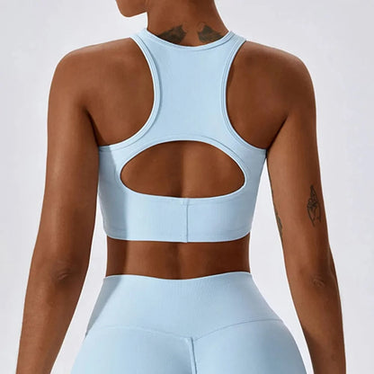 A light blue cropped athletic racerback tank top with a circular cutout on the back, shown on a person from behind.