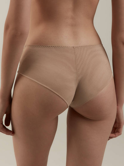 Nude-colored seamless briefs worn from the back against a plain light background.